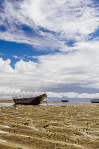 Boat moored on beach against sky