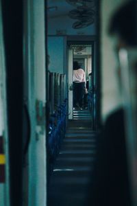 Rear view of man walking in corridor of building