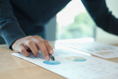 Midsection of businessman analyzing data at table in office