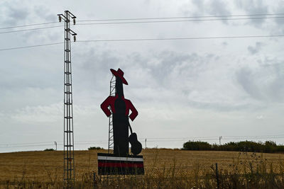 Low angle view of electricity pylon on field against sky