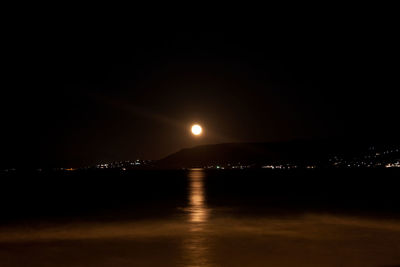 Illuminated sea against sky at night