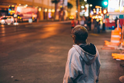 Rear view of man standing on street at night