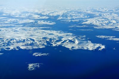 Aerial view of snowcapped mountains against blue sky