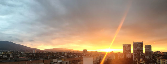 Low angle view of sunlight streaming through clouds during sunset