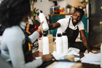 Male barber giving beauty product to female coworker in hair salon