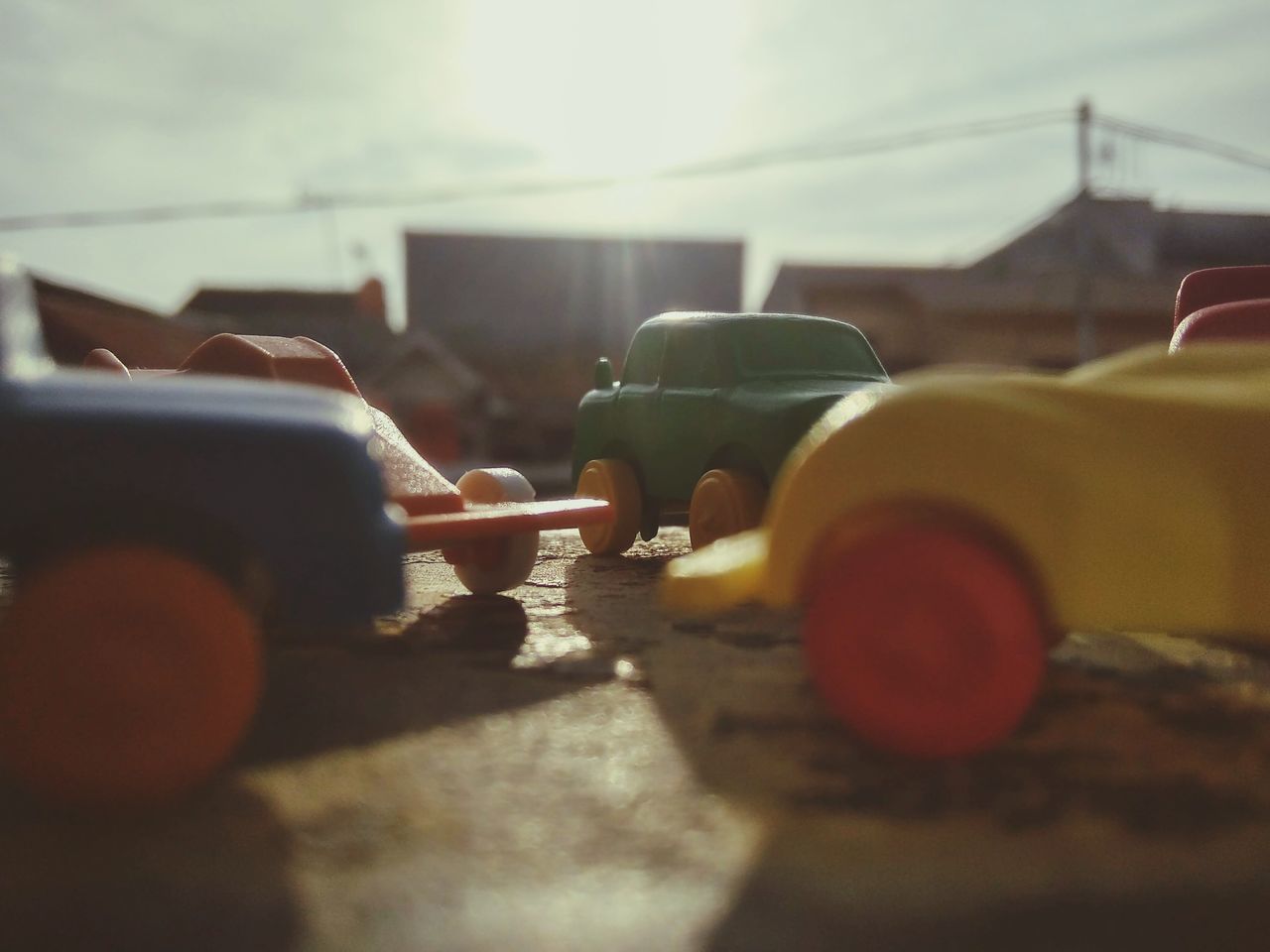 CLOSE-UP OF HAND HOLDING CAR ON STREET AGAINST SKY