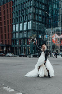 Full length of woman on road against buildings in city