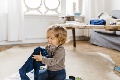 Girl holding jeans while sitting at home