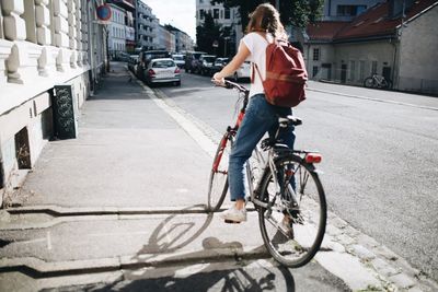 Young woman with bicycle on road in city