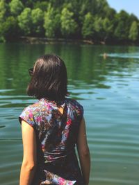 Rear view of woman standing by lake