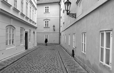 Man walking on road along buildings