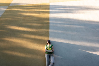 Low angle portrait of woman standing on wall