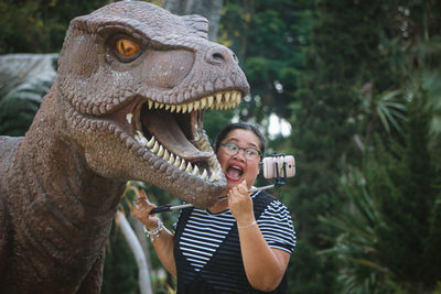 Woman taking selfie with dinosaur statue in park