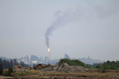 Smoke emitting from factory against sky