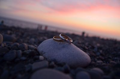 Close-up of pebbles on beach against sky during sunset