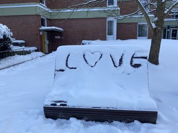 Text on snow covered field by building during winter