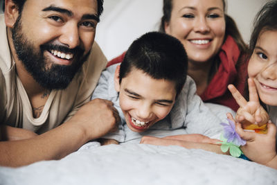 Happy parents with children lying on bed at home