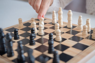 Cropped hand playing chess at table