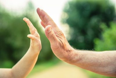 Close-up of man and boy high-fiving while standing outdoors
