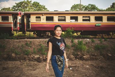 Portrait of smiling young woman standing on railroad track