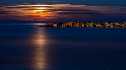 Moonlit sunrise at the sea on a clear sky evening