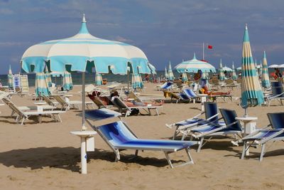 Chairs and tables on beach against sky