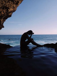 Side view of silhouette man on beach against clear sky