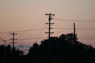 Low angle view of silhouette electricity pylon against sky