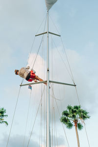 Low angle view of men on pole against sky