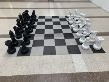 High angle view of chess pieces on tiled floor