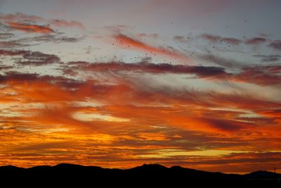 Low angle view of dramatic sky over silhouette landscape