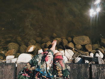 Low section of woman sitting on pier over lake