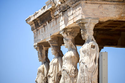 Low angle view of sculptures at historic building against clear sky