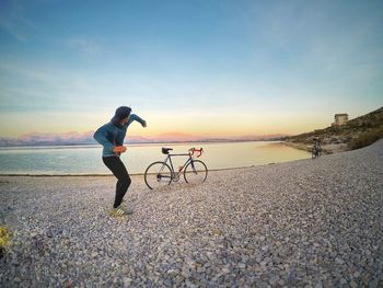 Full length of man standing by sea against sky during sunset