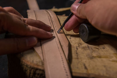 Close-up of craftsperson making belt in workshop