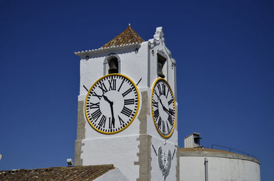 Low angle view of clock tower against clear blue sky