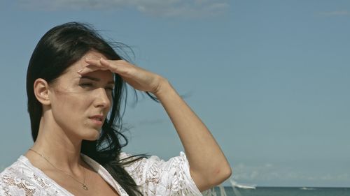 Portrait of young woman looking away against sky