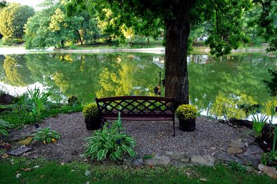 Sitting area with bench overlooking still waters on pond in overland park, kansas