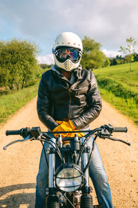 Man sitting on motorcycle at dirt road