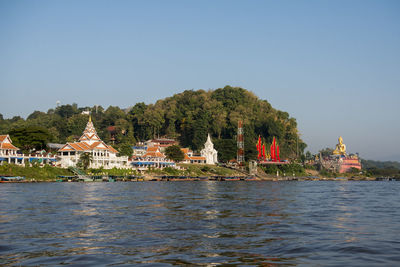 Scenic view of sea by buildings against clear sky