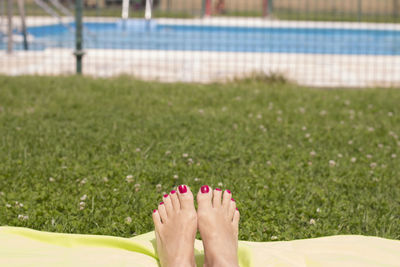 Low section of woman relaxing on towel over lawn