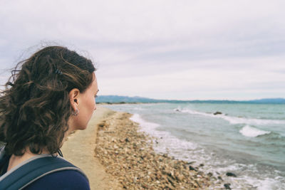 Girl looking at the sea on a cloudy and sad day with the rough sea