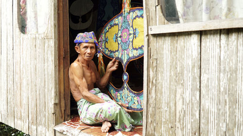 Shirtless man making craft product in workshop