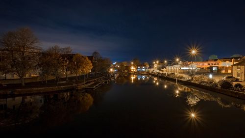 Illuminated bridge over river against sky at night