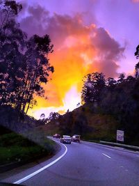 Scenic view of road against cloudy sky at sunset