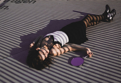 High angle view of woman with mirror lying outdoors