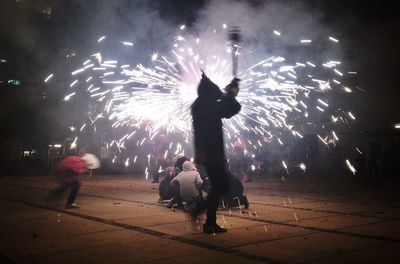 Silhouette of people watching firework display at night