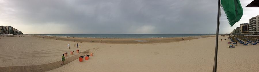 Panoramic view of people on beach against sky