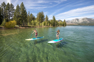 A man and woman stand up paddle boarding on lake tahoe, ca