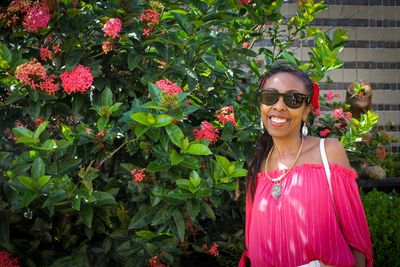 Portrait of smiling young woman standing against plants